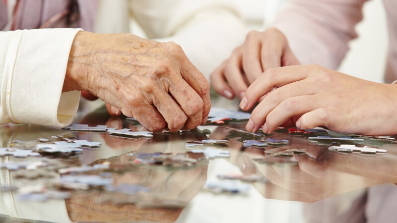 Old hands solving jigsaw puzzle
