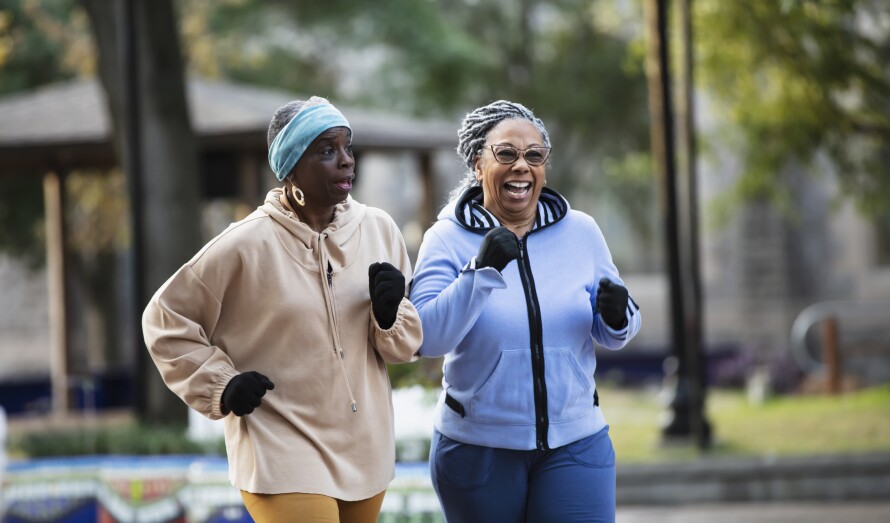 Two black senior women exercising, power walking in park